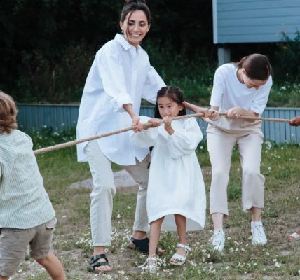 Family playing tug of war in backyard, showcasing teamwork and joy.