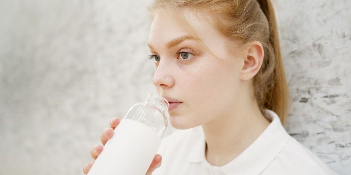 Close-up portrait of a young woman drinking water with a blurred background for copy space.