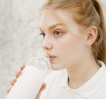 Close-up portrait of a young woman drinking water with a blurred background for copy space.