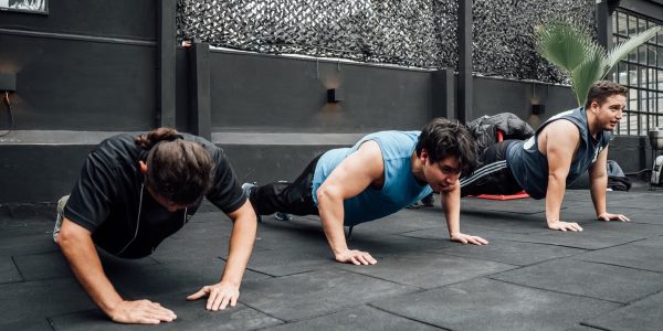 Men performing push-ups during a group workout session in Mexico City gym.